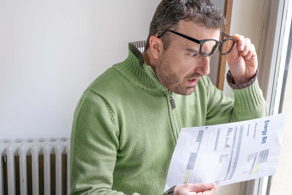 Shocked man reading some bills energy expenses Shocked man reading some bills energy expenses