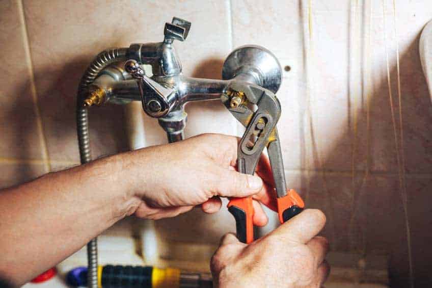 Man repair and fixing leaky faucet in bathroom