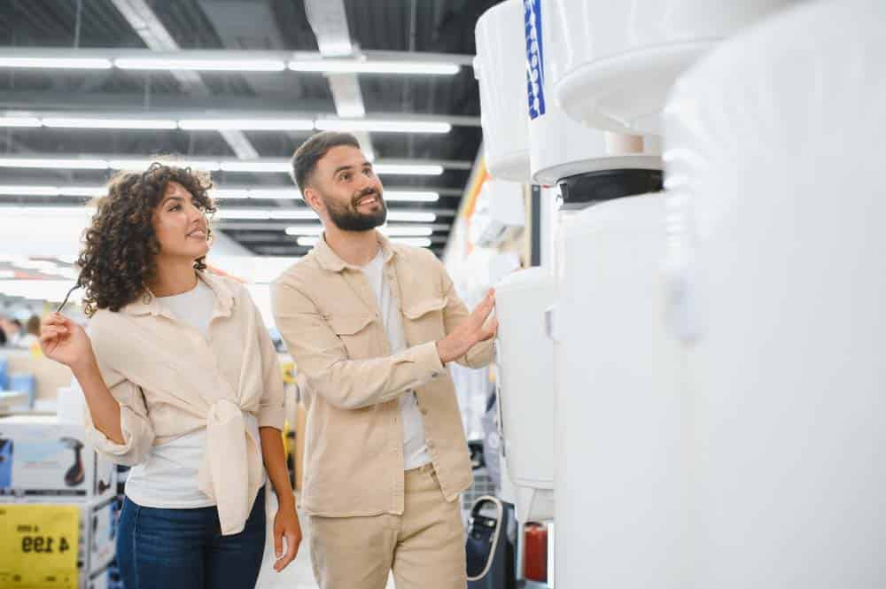 person looking at tankless and tank water heater units