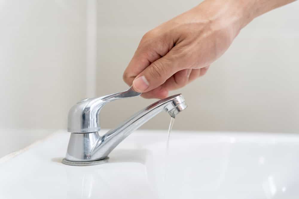 person turning off water valve