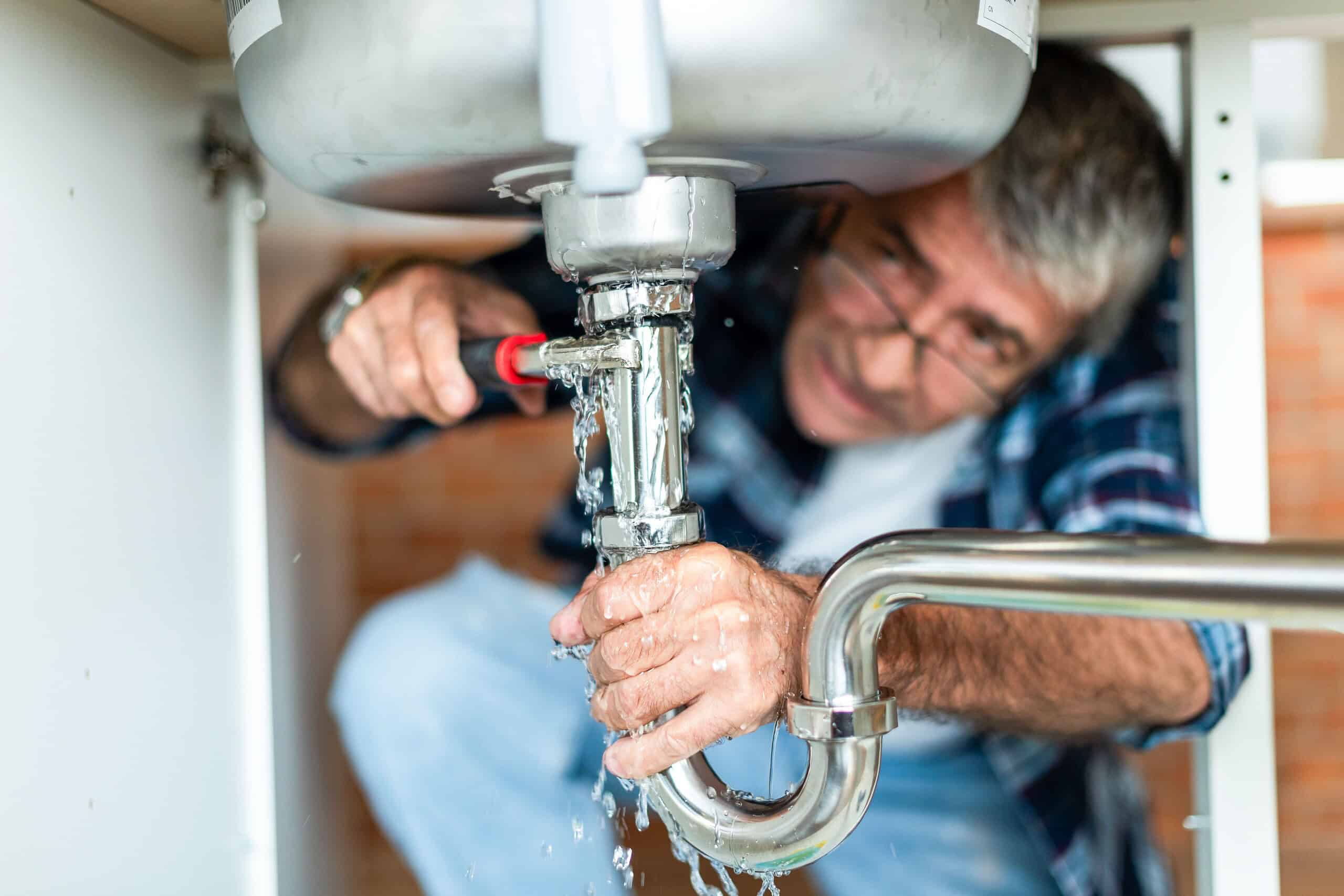 plumber fixing leaking kitchen sink